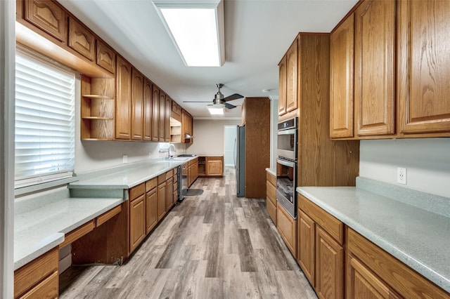 kitchen featuring brown cabinetry, appliances with stainless steel finishes, light wood-style floors, and light countertops