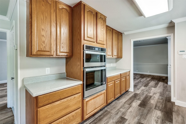kitchen featuring light countertops, double oven, crown molding, and dark wood-style floors