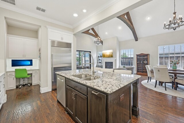 kitchen with white cabinets, a notable chandelier, a sink, stainless steel appliances, and open floor plan