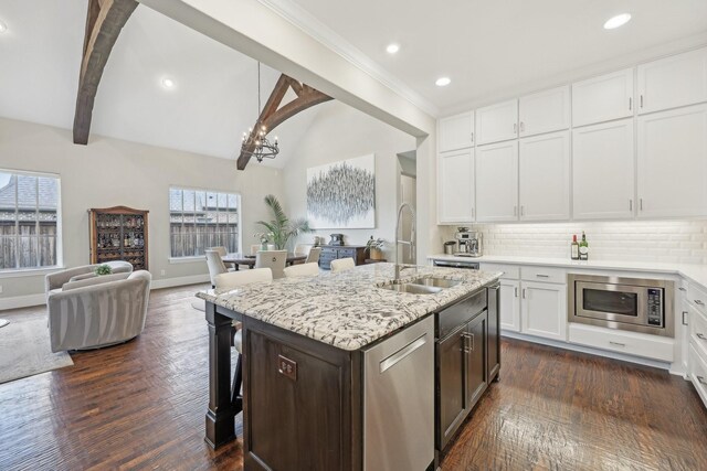 kitchen with a breakfast bar, a center island with sink, tasteful backsplash, custom range hood, and a sink