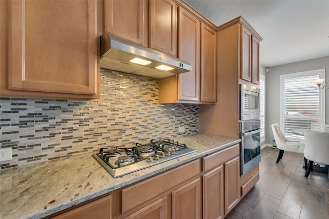 113 Bob White Ct, Rockwall, TX 75087 - kitchen with under cabinet range hood, light stone counters, appliances with stainless steel finishes, and tasteful backsplash