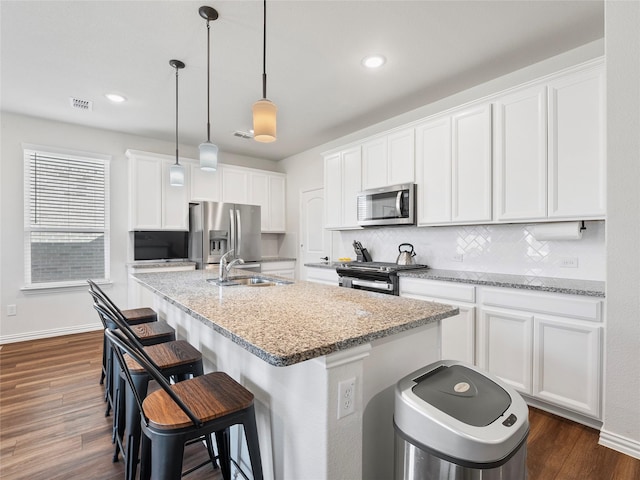 542 Freed Dr, Fate, TX 75087 - kitchen with appliances with stainless steel finishes, a sink, a center island with sink, a breakfast bar area, and tasteful backsplash