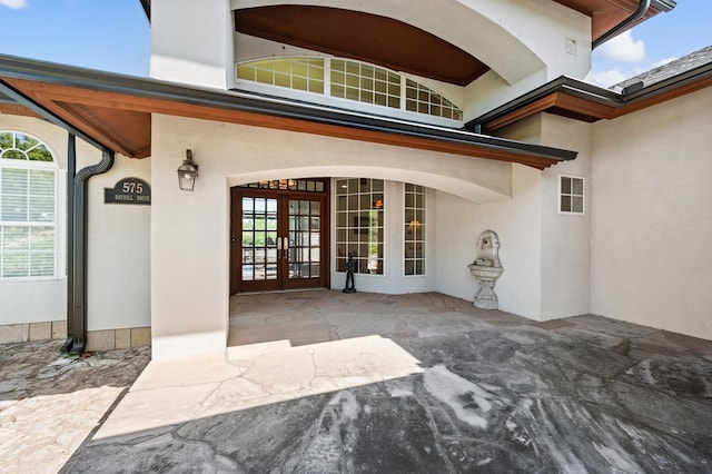 view of exterior entry featuring french doors, a patio area, and stucco siding