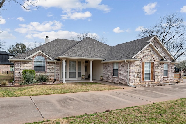 ranch-style house with a front lawn, roof with shingles, stone siding, and a chimney