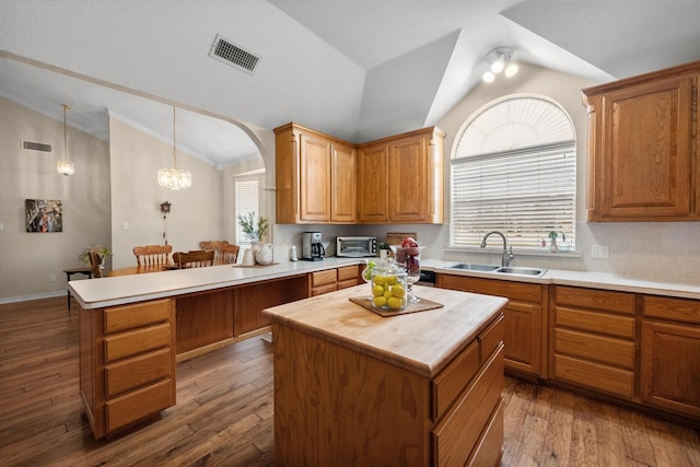 kitchen with a peninsula, a sink, vaulted ceiling, visible vents, and wood counters