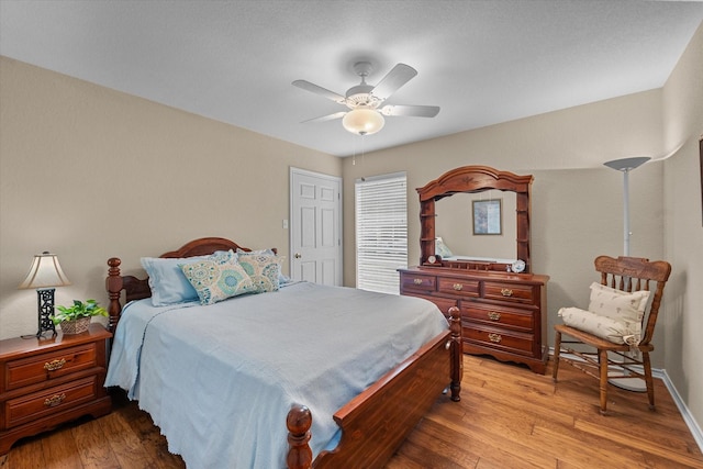 bedroom with light wood-style flooring, a ceiling fan, and baseboards