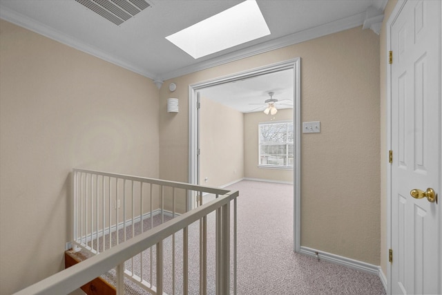 hall with a skylight, baseboards, ornamental molding, carpet flooring, and visible vents