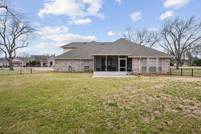 rear view of house with a sunroom, a fenced backyard, roof with shingles, and a lawn
