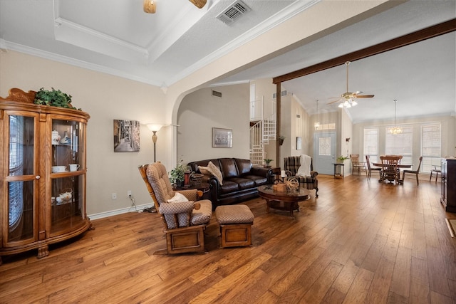 living room featuring light wood-style flooring, arched walkways, visible vents, stairway, and ceiling fan