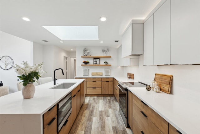 5724 Still Forest Dr, Dallas, TX 75252 - kitchen featuring range with electric cooktop, stainless steel microwave, modern cabinets, a sink, and a skylight