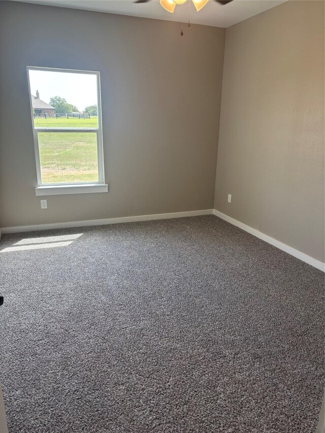 carpeted spare room with a ceiling fan and baseboards