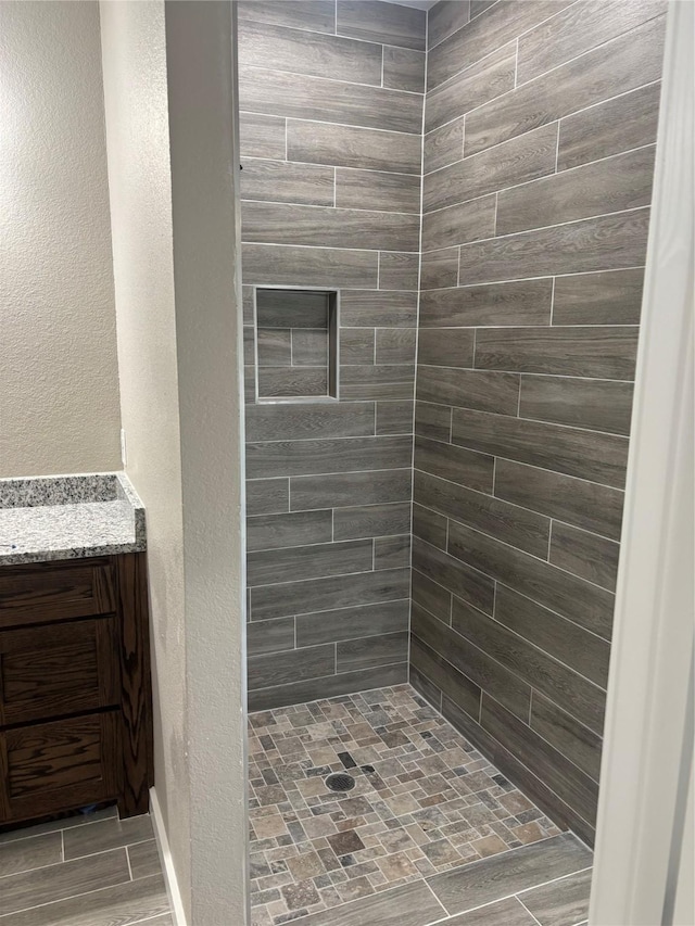 bathroom featuring a shower stall, vanity, and a textured wall