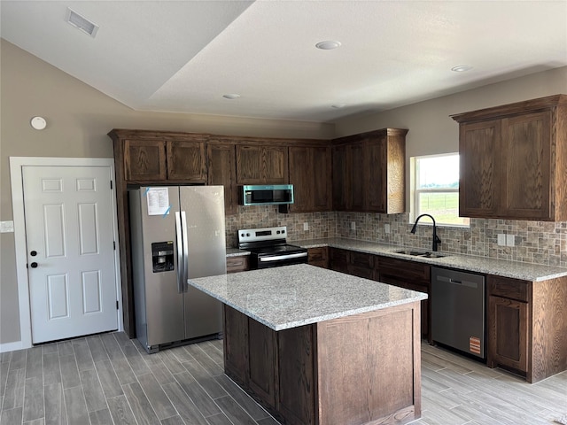 kitchen featuring backsplash, stainless steel appliances, wood tiled floor, and a sink