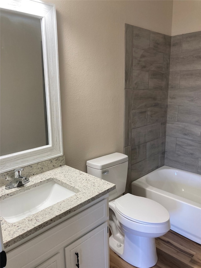 3833 Dana Ct, Abilene, TX 79606 - bathroom featuring a textured wall, vanity, toilet, shower / bath combination, and wood finished floors