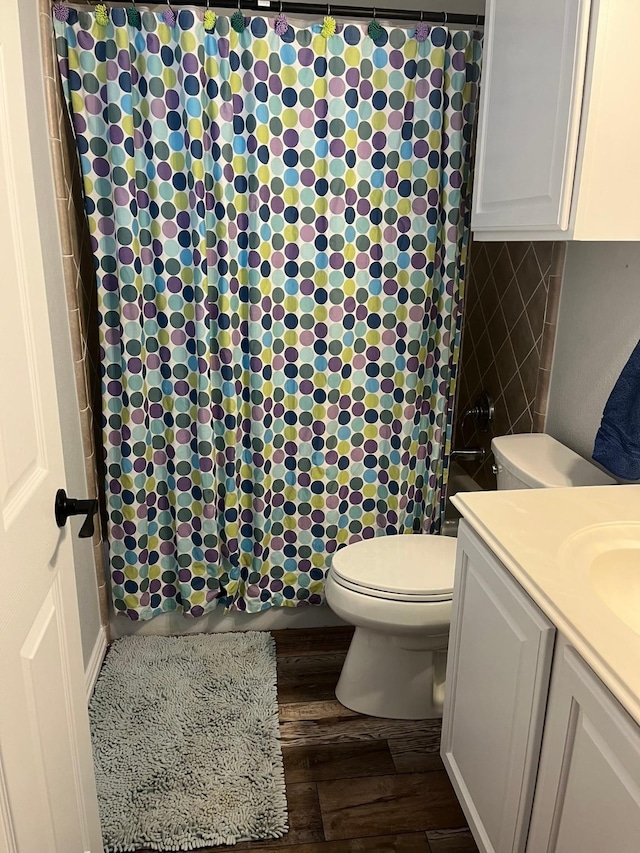 full bath with a shower with shower curtain, wood finished floors, toilet, and vanity