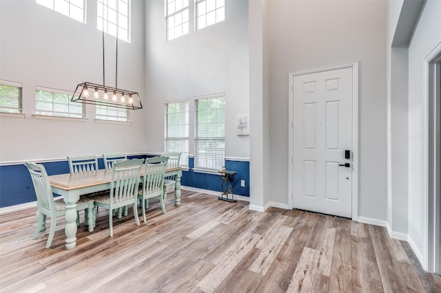 dining area featuring plenty of natural light, wood finished floors, a high ceiling, and baseboards