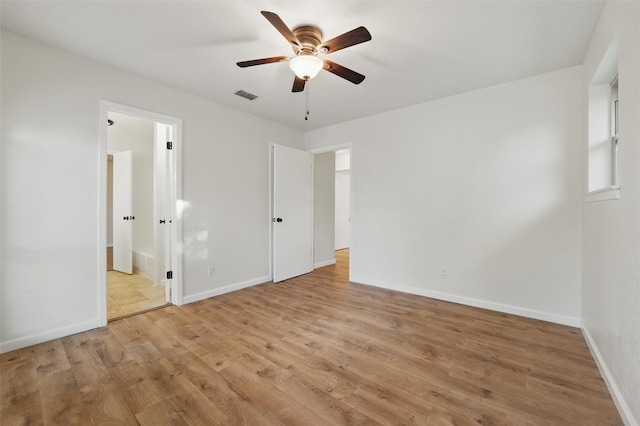 unfurnished bedroom with light wood finished floors, visible vents, a ceiling fan, ensuite bath, and baseboards