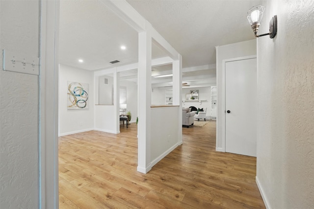hall with light wood-style flooring, baseboards, visible vents, recessed lighting, and a textured wall