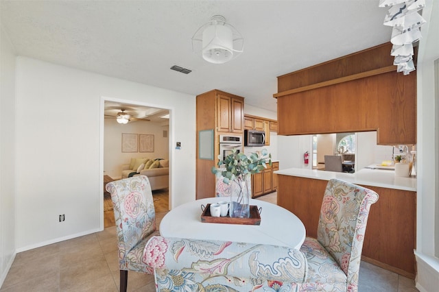 dining space with visible vents, a ceiling fan, baseboards, and light tile patterned floors