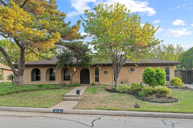 single story home featuring brick siding, a front lawn, and covered porch