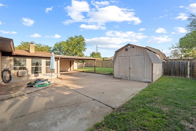 view of patio / terrace featuring a storage unit, an outbuilding, a fenced backyard, cooling unit, and driveway