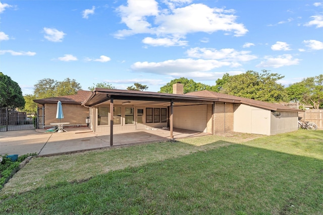 rear view of house featuring fence, brick siding, an attached garage, a yard, and a sunroom