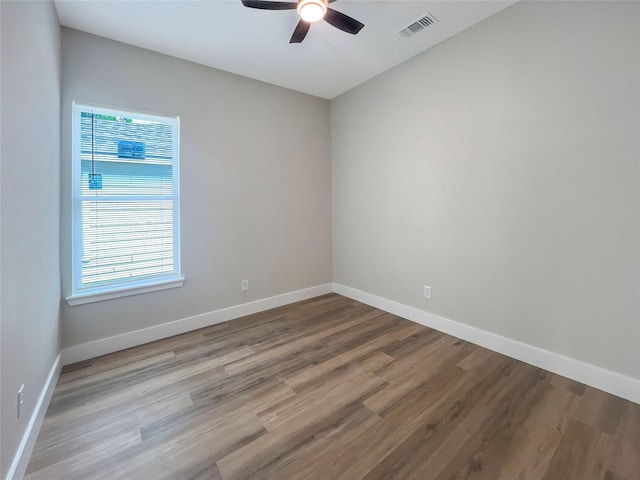 empty room with ceiling fan, baseboards, wood finished floors, and visible vents