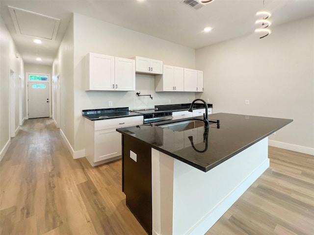 kitchen featuring dark countertops, a sink, stainless steel electric stove, light wood finished floors, and baseboards