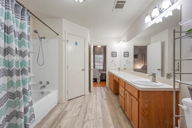 bathroom with a sink, double vanity, visible vents, wood finished floors, and shower / tub combo with curtain