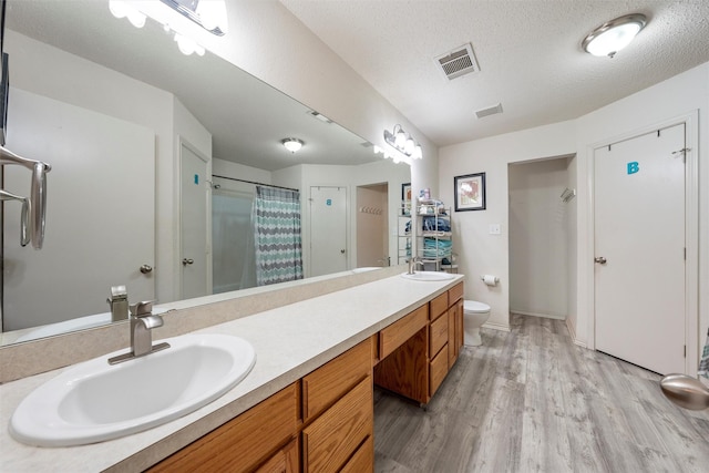 full bathroom with visible vents, wood finished floors, a sink, and toilet
