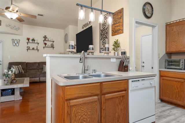 kitchen featuring light wood-style flooring, a sink, open floor plan, visible vents, and white dishwasher