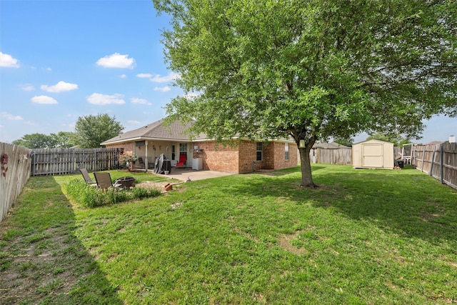 view of yard featuring a patio area, a storage shed, an outdoor fire pit, a fenced backyard, and an outbuilding