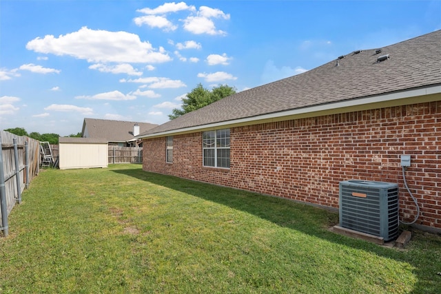 view of yard with a storage shed, an outbuilding, central AC, and a fenced backyard