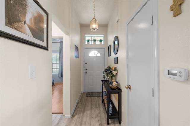 entryway with baseboards, a textured ceiling, and light wood-style floors
