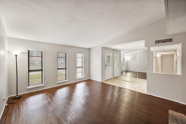 6606 Greenfield Dr, Arlington, TX 76016 - unfurnished living room featuring wood finished floors, visible vents, lofted ceiling, and baseboards