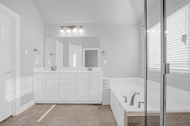 bathroom featuring a sink, tile patterned flooring, a garden tub, double vanity, and vaulted ceiling