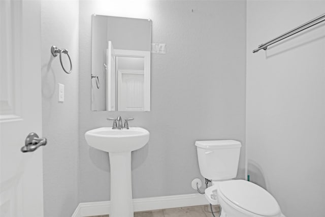 bathroom with toilet, baseboards, tile patterned floors, and a sink