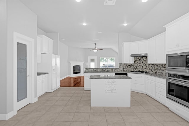 kitchen featuring lofted ceiling, a ceiling fan, a sink, stainless steel appliances, and tasteful backsplash