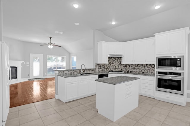 kitchen featuring a center island, a sink, stainless steel appliances, backsplash, and lofted ceiling