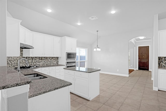 kitchen with built in microwave, under cabinet range hood, stainless steel oven, a sink, and backsplash