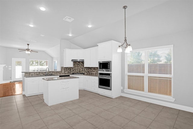 kitchen featuring a sink, stainless steel appliances, visible vents, decorative backsplash, and vaulted ceiling