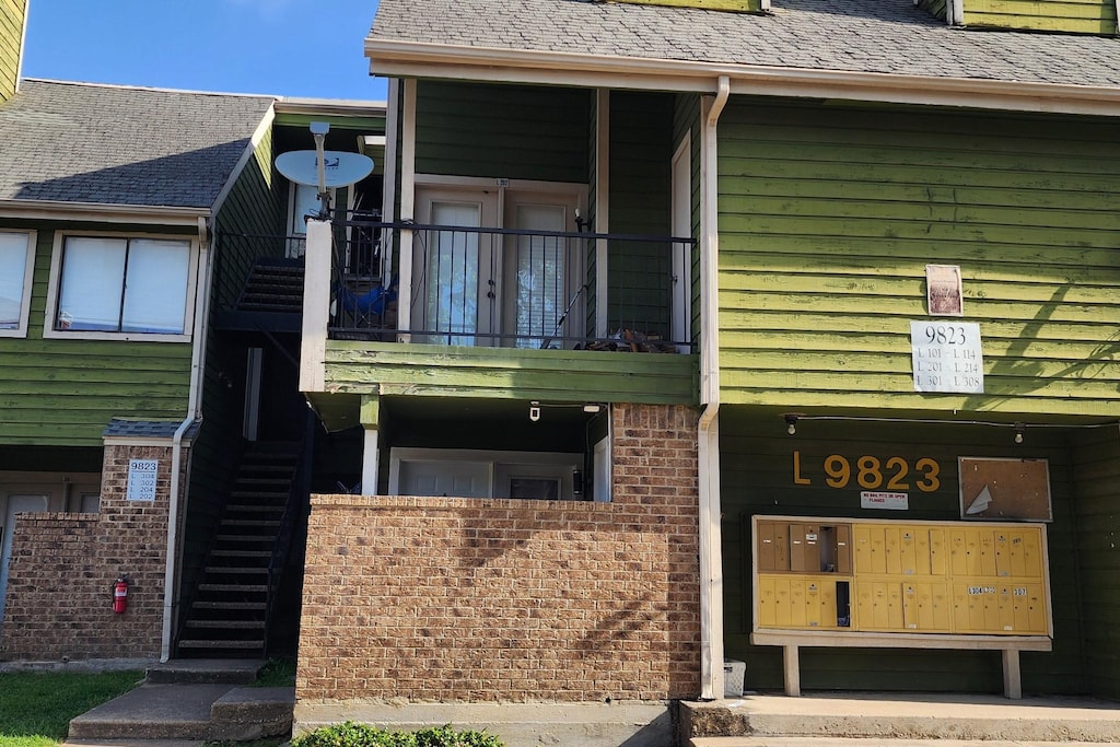 9813 Walnut St Unit 201, Dallas, TX 75243 - doorway to property featuring a shingled roof and a balcony
