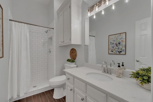 bathroom with wood finished floors, vanity, toilet, and tiled shower