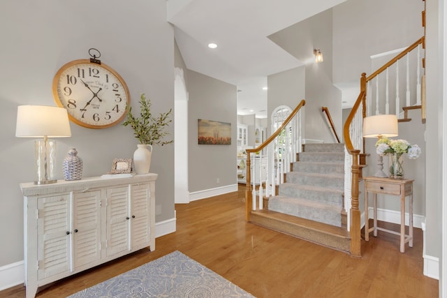 stairway featuring baseboards, wood finished floors, and recessed lighting