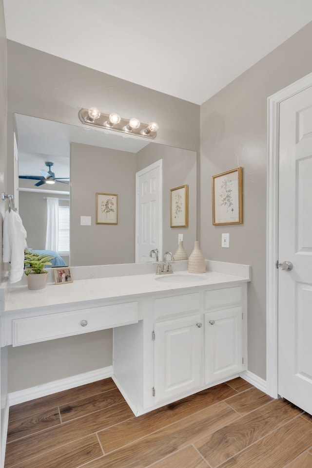 bathroom with baseboards, wood finished floors, vanity, and ceiling fan