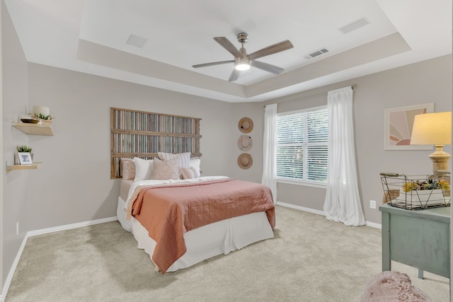 bedroom featuring baseboards, light carpet, visible vents, and a raised ceiling