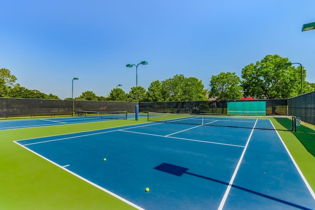 view of tennis court with community basketball court and fence