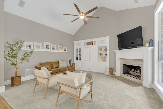 carpeted living room featuring a tile fireplace, visible vents, a ceiling fan, and high vaulted ceiling