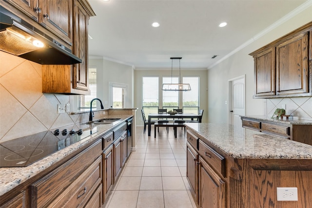 kitchen featuring a sink, backsplash, light stone countertops, black electric stovetop, and under cabinet range hood