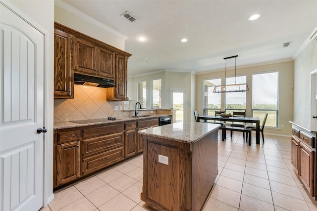 kitchen with a center island, under cabinet range hood, black appliances, ornamental molding, and visible vents
